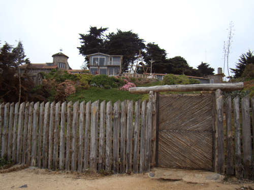 Pelo portão de madeira Neruda tinha acesso à praia e às pedras que o protegiam do furor oceânico e, simultaneamente, emolduravam o mundo líquido que tanto amou. simultaneamente o l